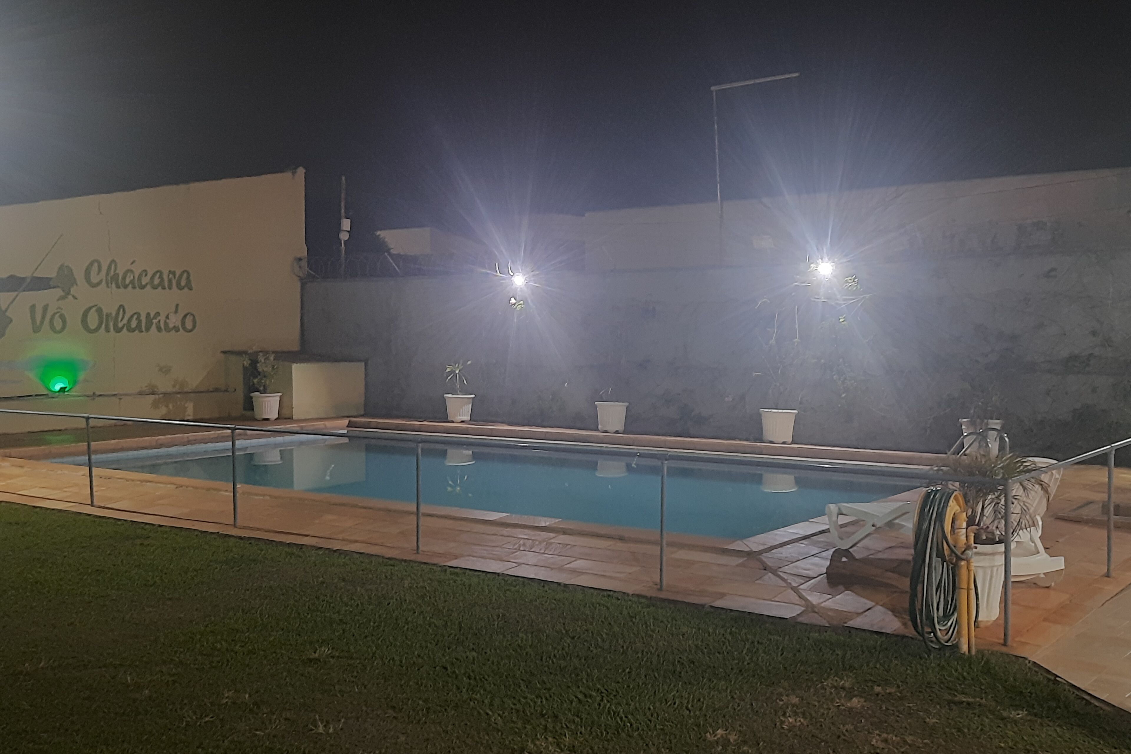 A swimming pool with a glass barrier, potted plants, and a wall with text.