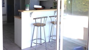 Cocina con una isla central, dos taburetes de bar y un ventanal corredero que da a un balcón.