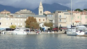 Un puerto deportivo con barcos amarrados, una iglesia con campanario y edificios con balcones.