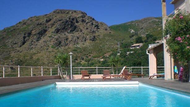 Una piscina con tumbonas de madera y vistas a la montaña.