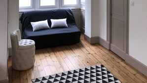 Una habitación con un sofá azul oscuro, un otoman blanco y una alfombra de diseño geométrico.