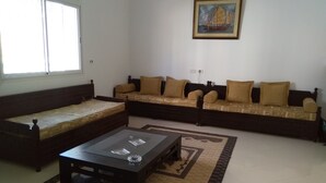 A living room with a sofa set, a glass coffee table, and a rug. - Maison des Tulipes (Béni Khiar)