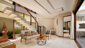 Uma sala de estar ampla com escada, um conjunto de sofás e uma mesa de centro.