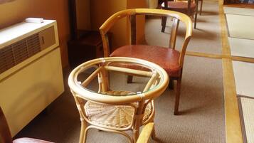 A room with a traditional Japanese tatami mat floor, a wooden table, and two chairs.