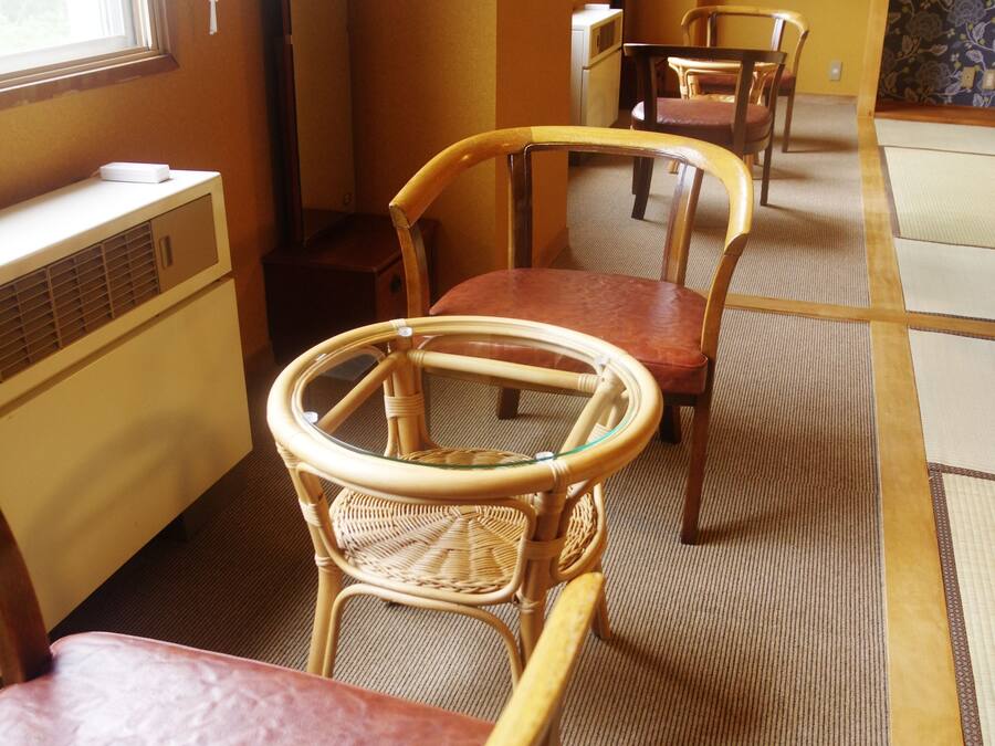 A room with a traditional Japanese tatami mat floor, a wooden table, and two chairs.