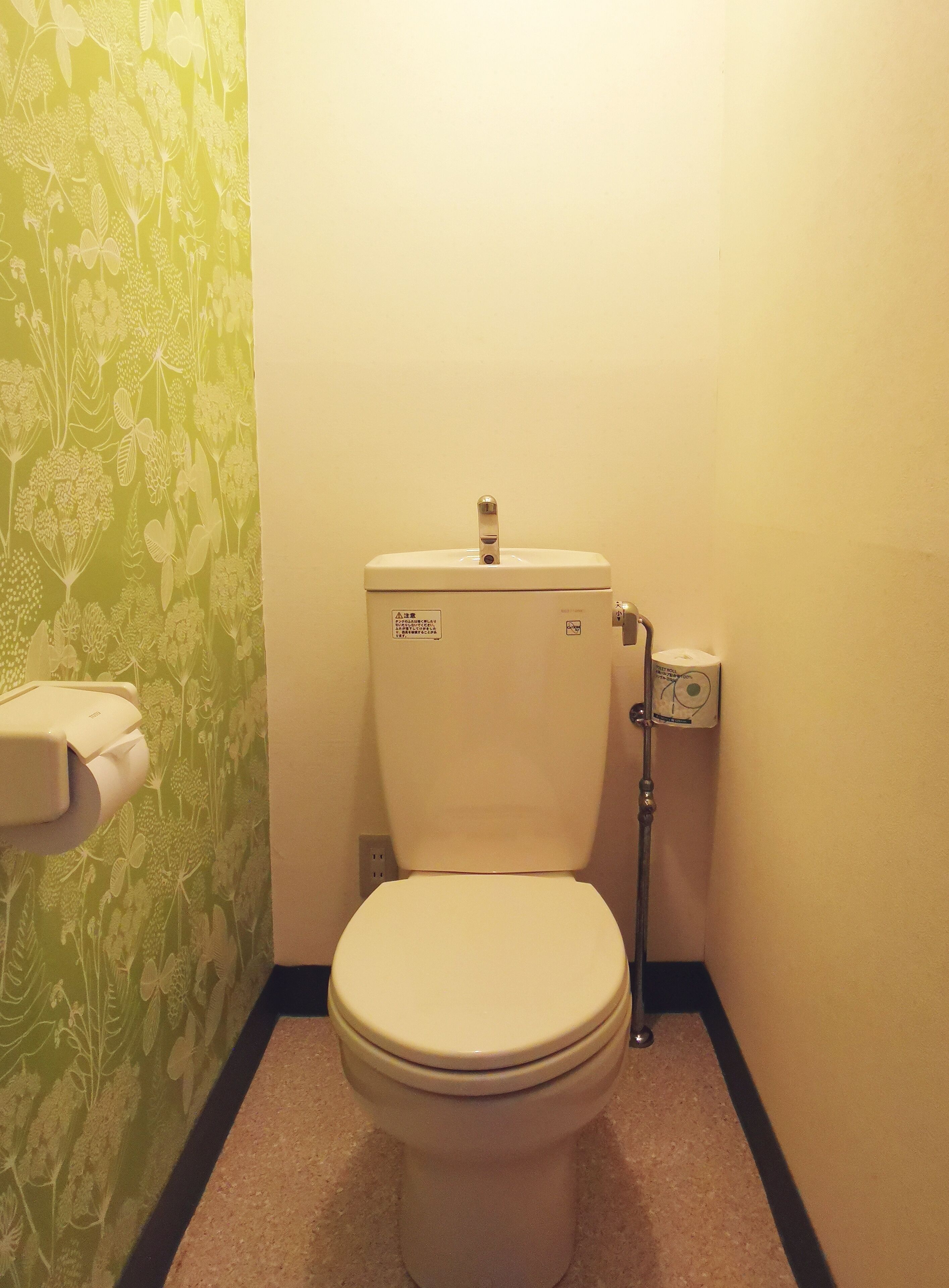 A toilet with a flush handle and a paper towel dispenser.