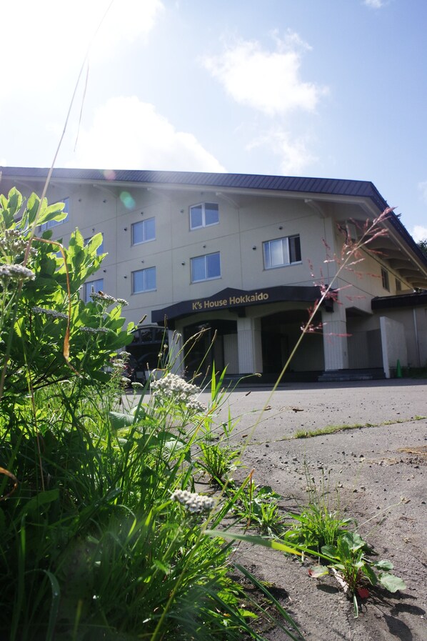 A building with a sign reading "K's House Hokkaido" and a parking area in front. - K's House Hokkaido - Asahidake Onsen Hostel (Higashikawa)