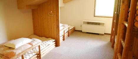 A room with two bunk beds, a window, and a wall-mounted air conditioner.