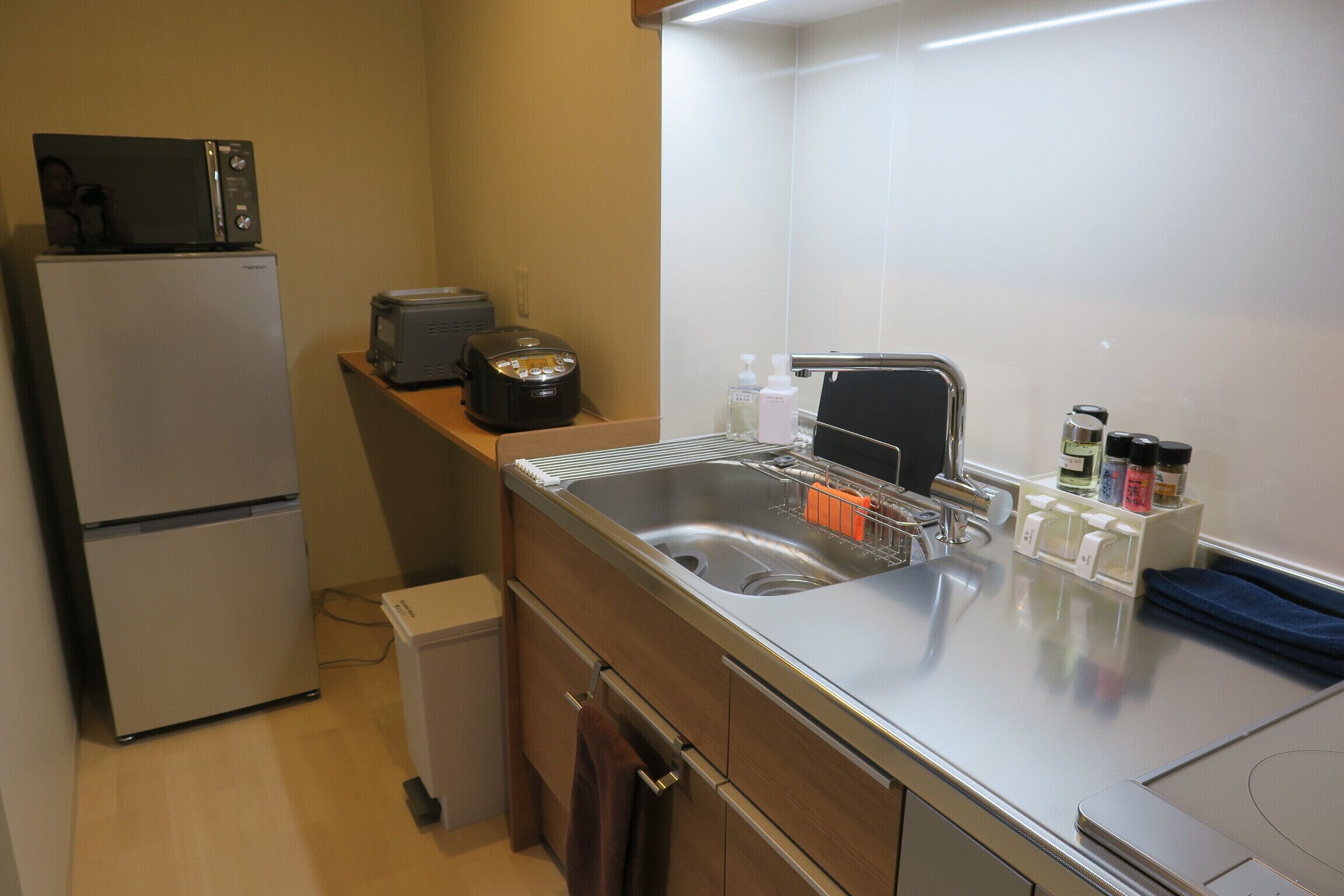 A compact kitchen with a refrigerator, microwave, toaster, sink, and a small cabinet.