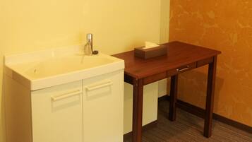 A small bathroom with a white sink, a mirror, and a wooden table with a tissue box.