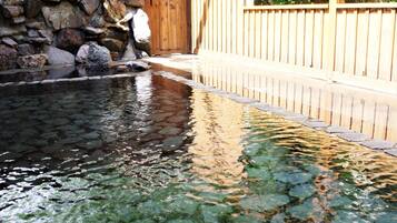 Relax by the serene pool surrounded by lush vegetation and a wooden fence.