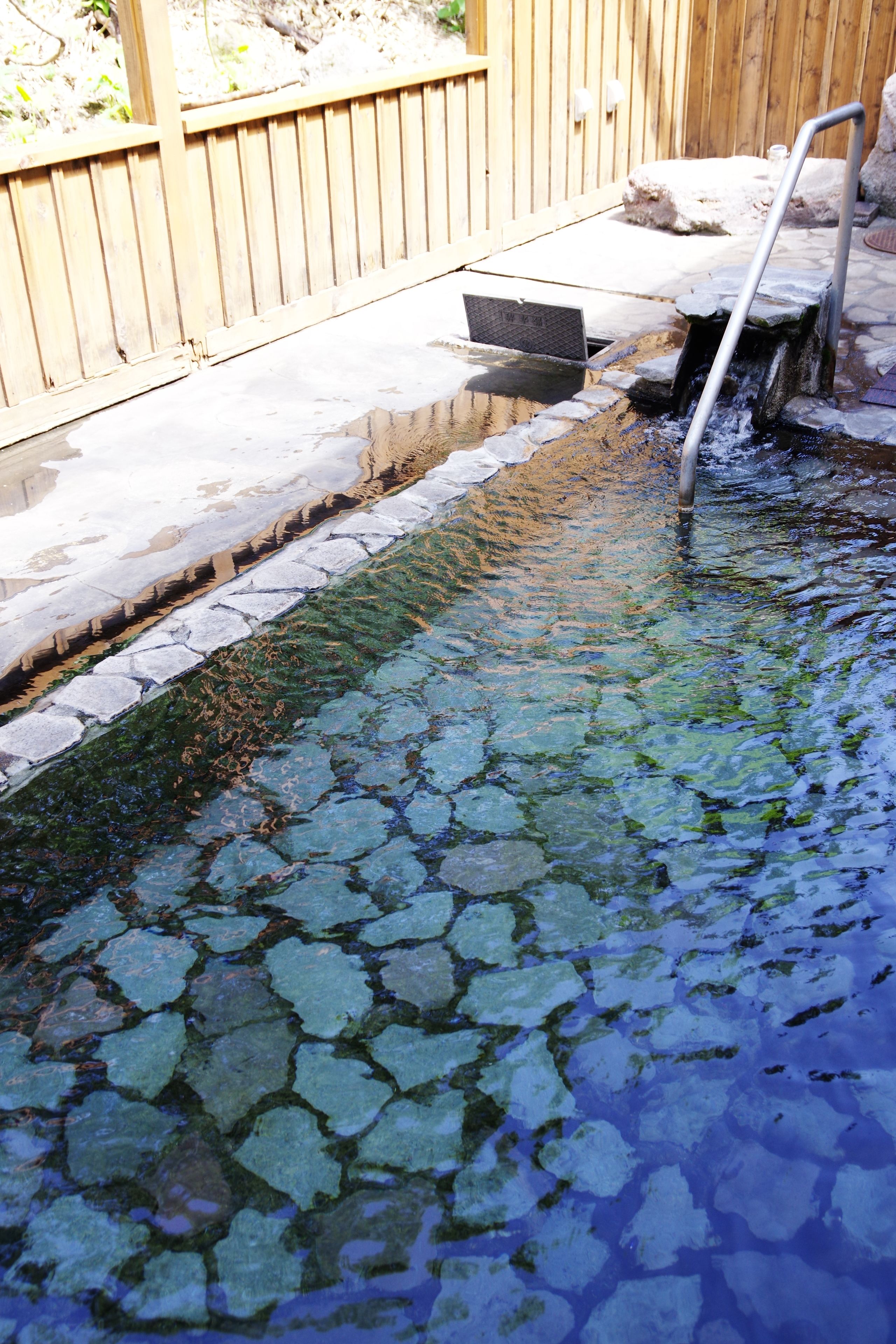 A small outdoor pool with a wooden deck and a metal ladder.
