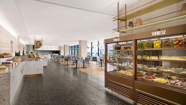 En moderne cafeteria med en marmordisk, glasudstillinger med mad og et fiskebensmønstret gulv.