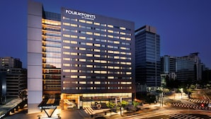 Et moderne hotel med et tydeligt skilt med 'Four Points by Sheraton', med et gittermønster af vinduer og en godt oplyst indgang.