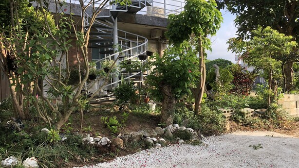 A garden with a spiral staircase, various plants, and a gravel path. - Clara Terrace (Ishigaki)