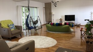 A modern living room with a sofa, a hanging chair, a TV, and a globe on a small table. - Clara Terrace (Ishigaki)