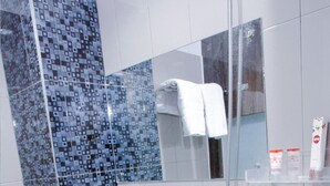 A modern bathroom with a toilet, shower, and a tiled wall with a geometric pattern. - OYO 861 R Four Hotel (Palu)