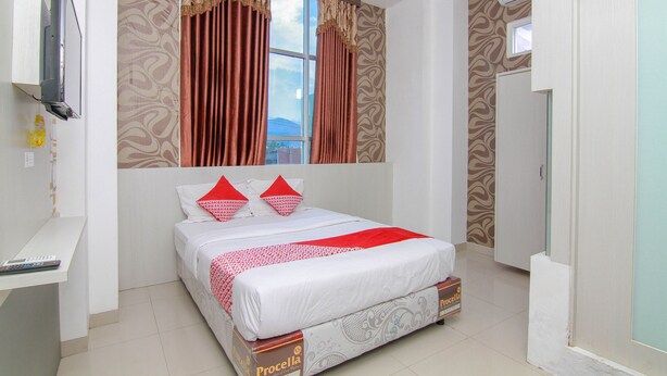 A bedroom with a bed, curtains, a TV, and a window. - OYO 861 R Four Hotel (Palu)