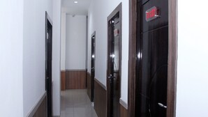 A hallway with wooden doors and white walls. - OYO 861 R Four Hotel (Palu)
