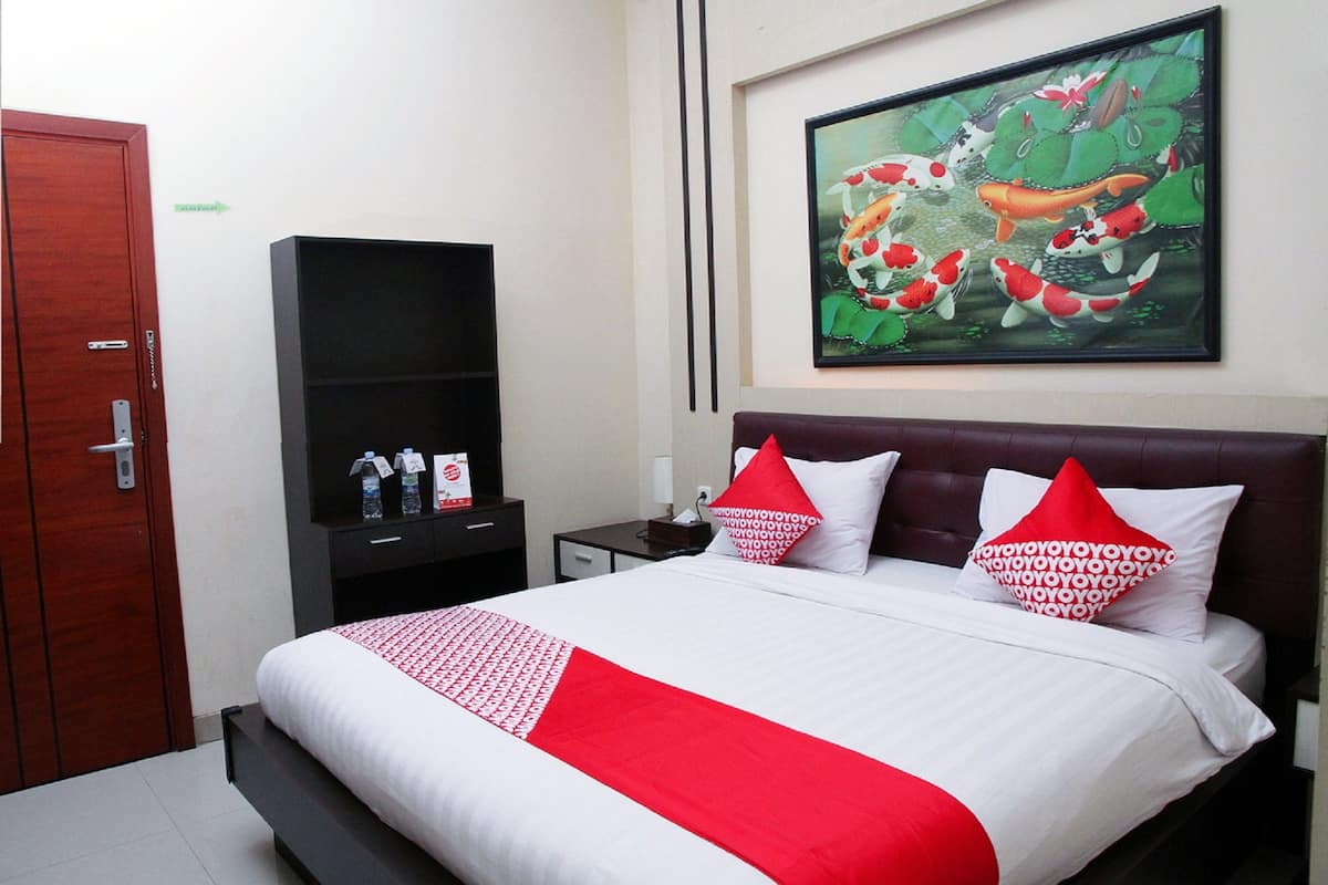 A hotel room with a bed, a TV stand, a painting, and a door.