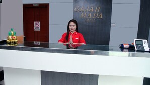 Een receptiebalie bij het Gajah Mada Hotel, met een rookvrij bord, een telefoon en een decoratieve ananasopstelling.