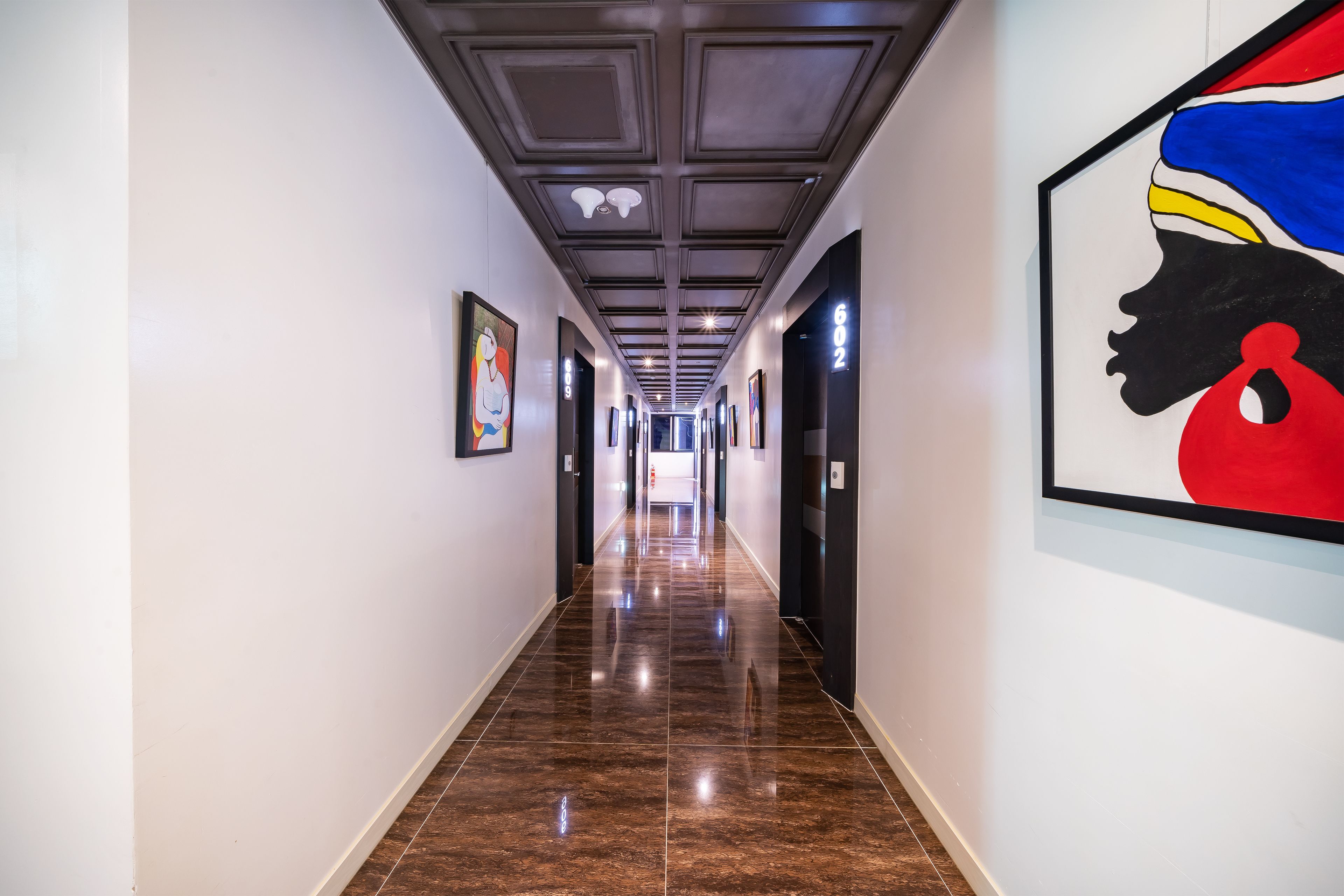 A long, narrow hallway with a polished floor and a ceiling with recessed lighting.