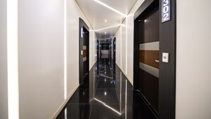 A modern hotel hallway with a reflective black floor, white walls, and a number sign indicating room 302. - Seattle B Hotel (Busan)
