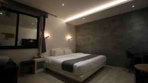 A modern bedroom with a large bed, bedside tables, a desk, and a mirror. - Seattle B Hotel (Busan)