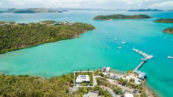 Vista aérea de una zona costera con un puerto deportivo, barcos y un edificio con paneles solares.