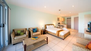 A hotel room with a bed, two sofas, a coffee table, and a TV. - Baybliss Studio 2 (Shute Harbour)