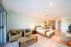 Habitación de hotel con cama, dos sofás, una mesa de centro y televisor.