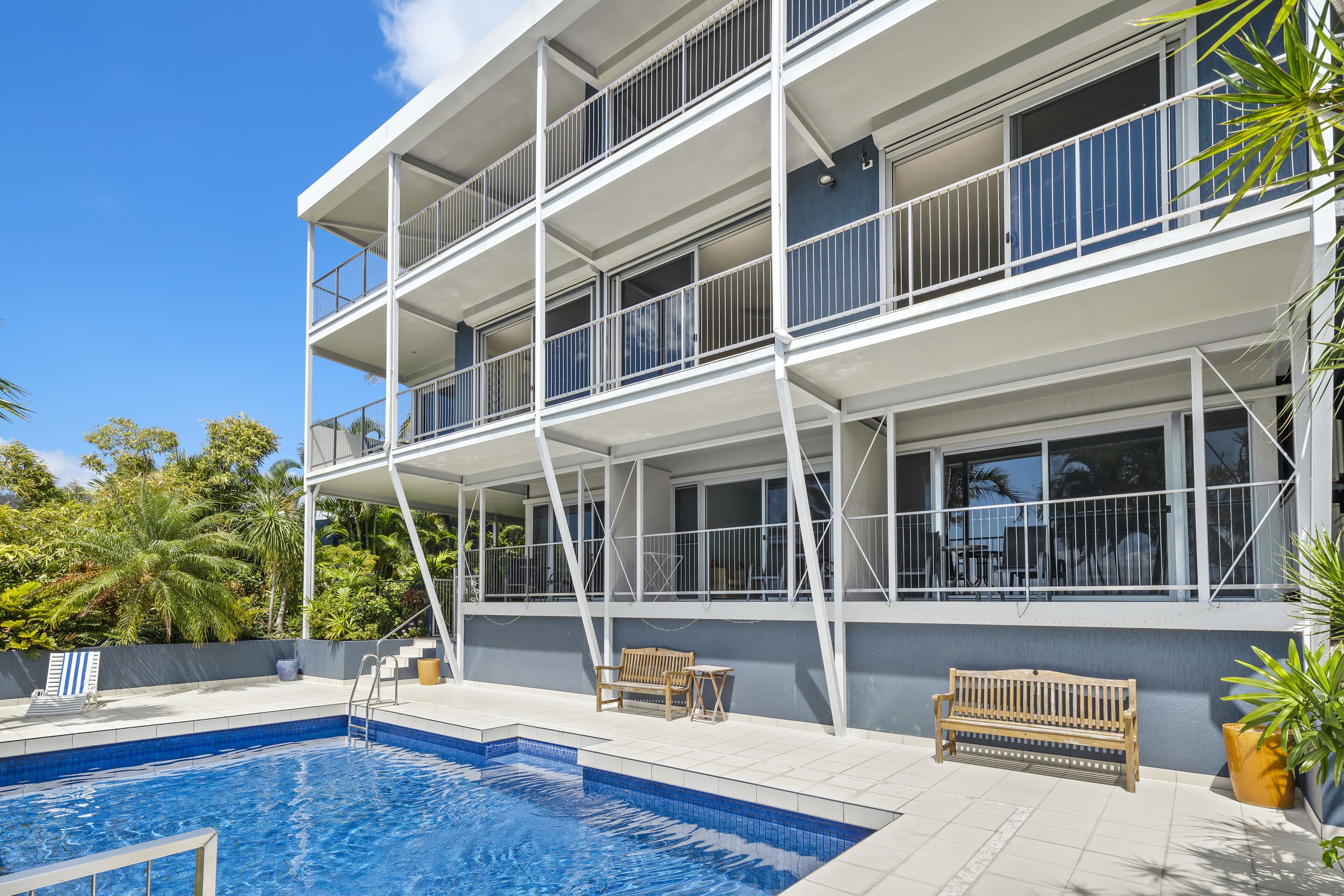 A modern building with a pool, outdoor seating, and balconies.