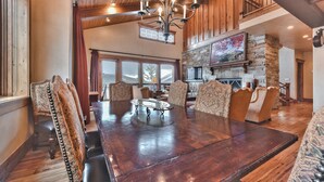 A spacious dining area with a large wooden table, patterned chairs, and a chandelier. - Luxury Townhome, Gourmet Kitchen, Hot Tub, Recreation, Great Location! (Deer Valley)