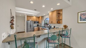 A modern kitchen with a central island, wooden cabinets, and a stainless steel refrigerator. - Santa Susana | West Sedona Townhome w/ Pool, Hot Tub & Red Rock Views (Sedona)