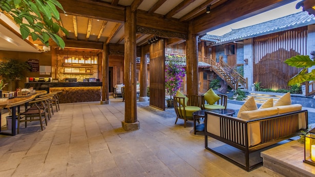 A traditional wooden interior with a bar area, seating, and a staircase leading to an upper level. - Lijang First Bay Hotel (Lijiang)