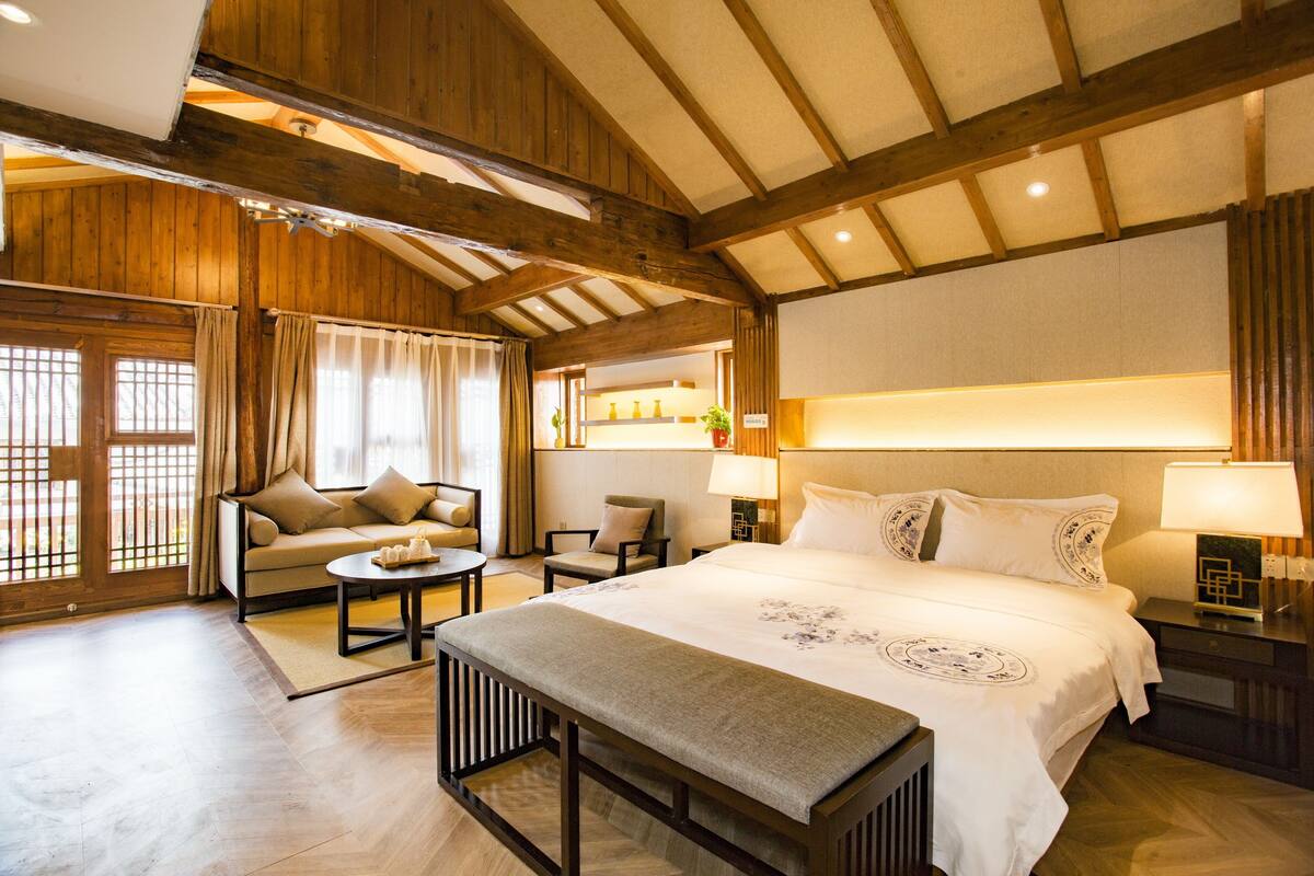 Una habitació d'hotel àmplia amb un llit gran, un sofà, una panxa i una taula de menjador.
