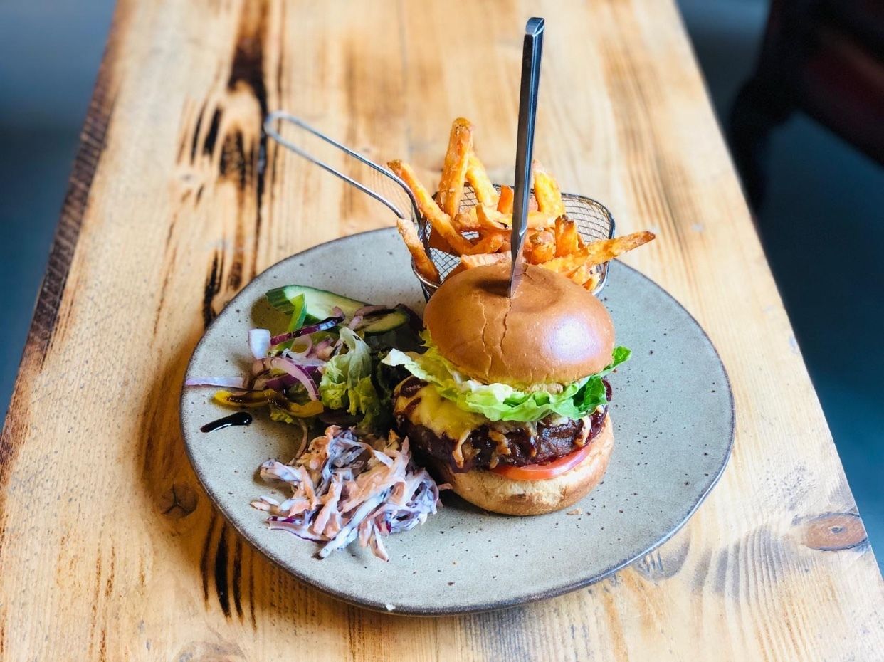 A burger with fries and a side salad on a plate.
