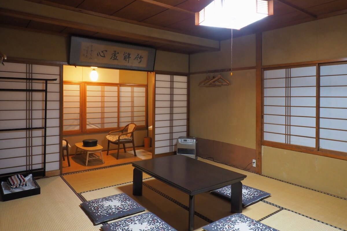 Une pièce de style japonais traditionnel, avec un sol recouvert de tatamis, une table basse, une chaise et une porte coulissante.