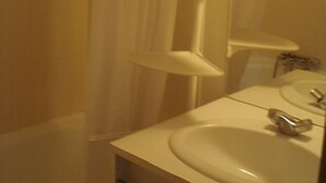 Een badkamer met een wit wastafelmeubel, spiegel en douchegordijn.