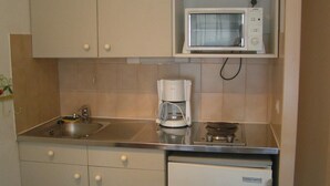 Een kleine keuken met een magnetron, koffiezetapparaat en een koelkast.