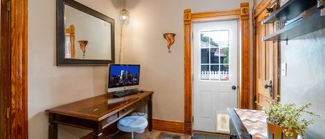 A room with a wooden desk, a computer, a chair, a door, and a potted plant.