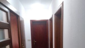 Un corridoio con porte in legno e pavimento piastrellato.
