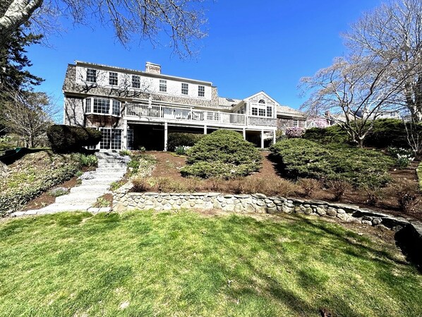 A large, two-story house with a covered porch and a stone retaining wall.