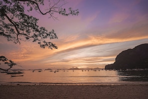 Una playa con barcos y un atardecer.