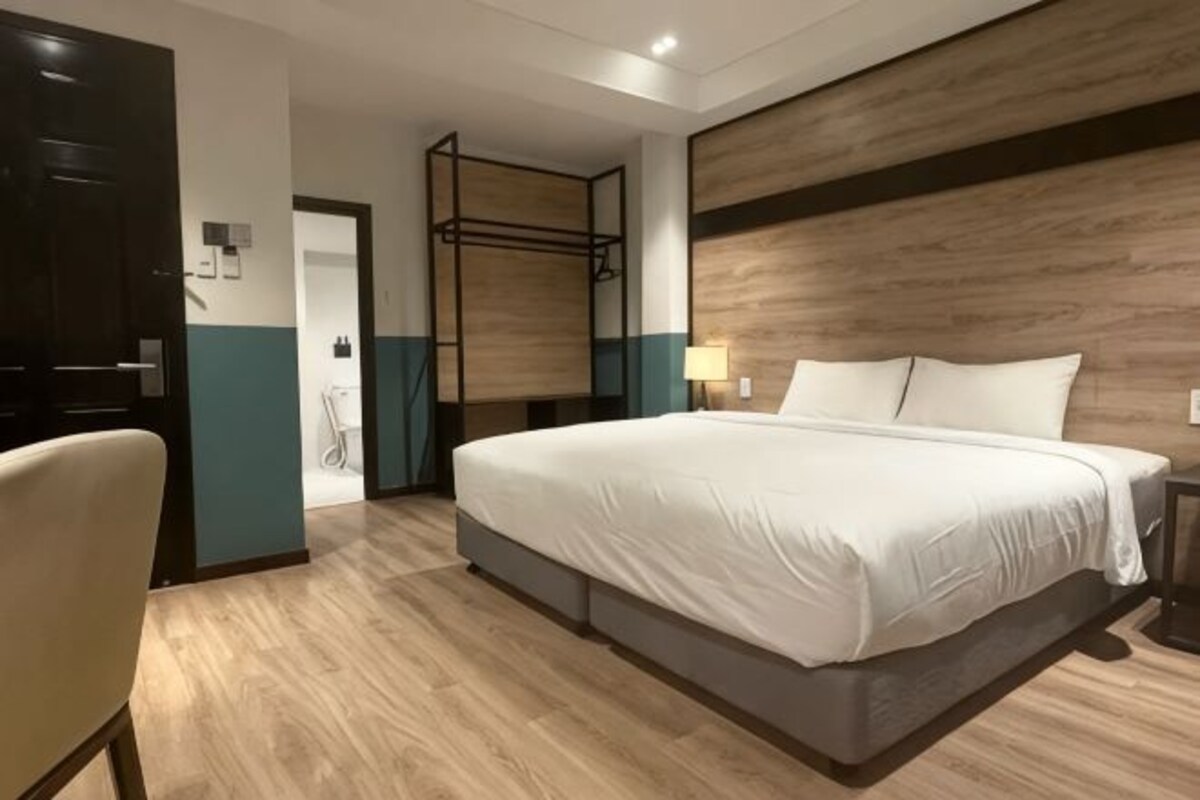 Une chambre d’hôtel avec un grand lit, un bureau et une armoire.