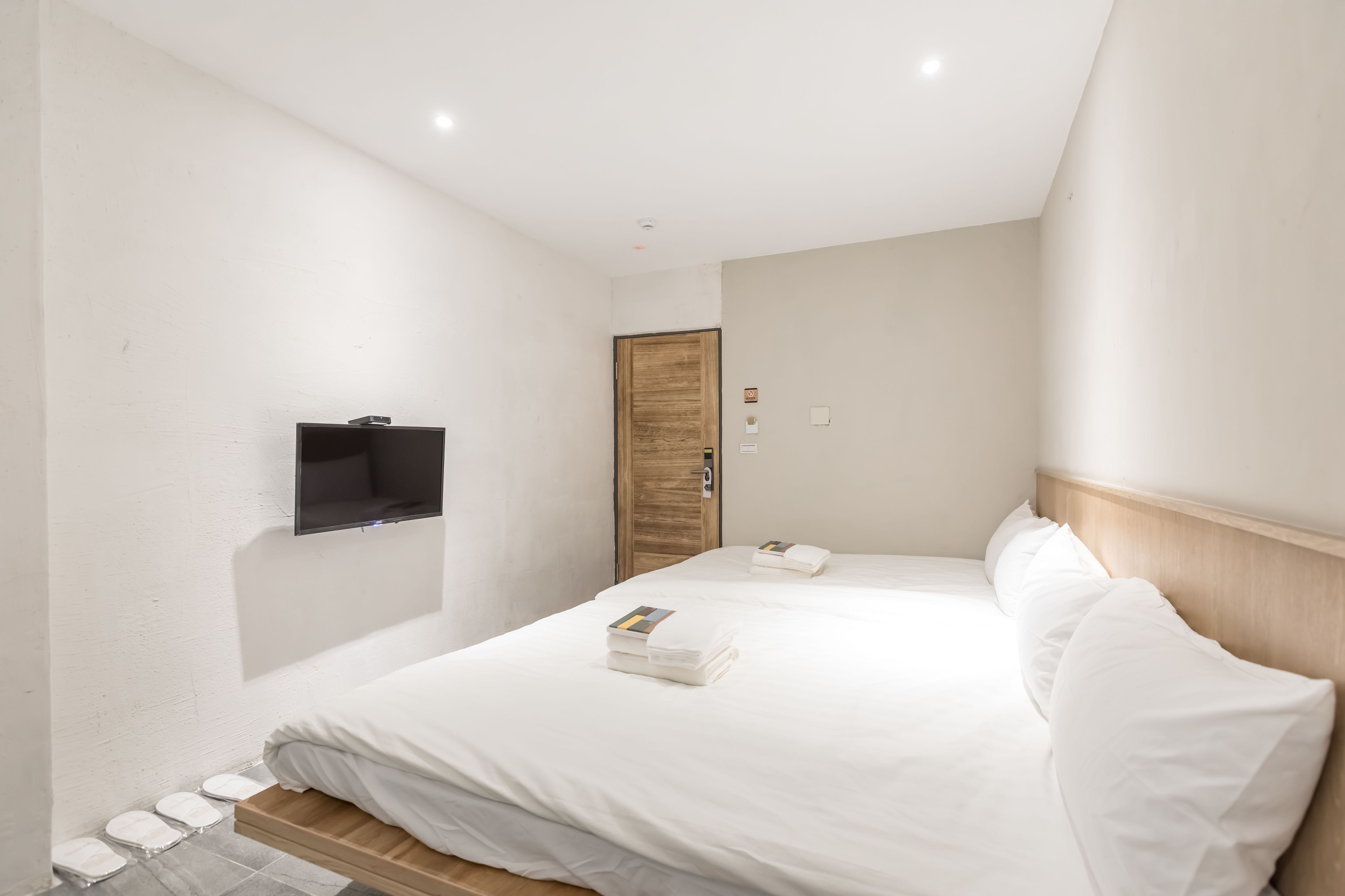 Una habitación de hotel con una cama, un televisor en la pared y una puerta de madera.