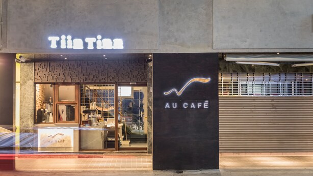 A storefront with a neon sign reading "Tia Tia" and a sign for "AU CAFÉ" with a line graph design.
