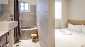 A modern bathroom with a bathtub, shower, and a small stool.