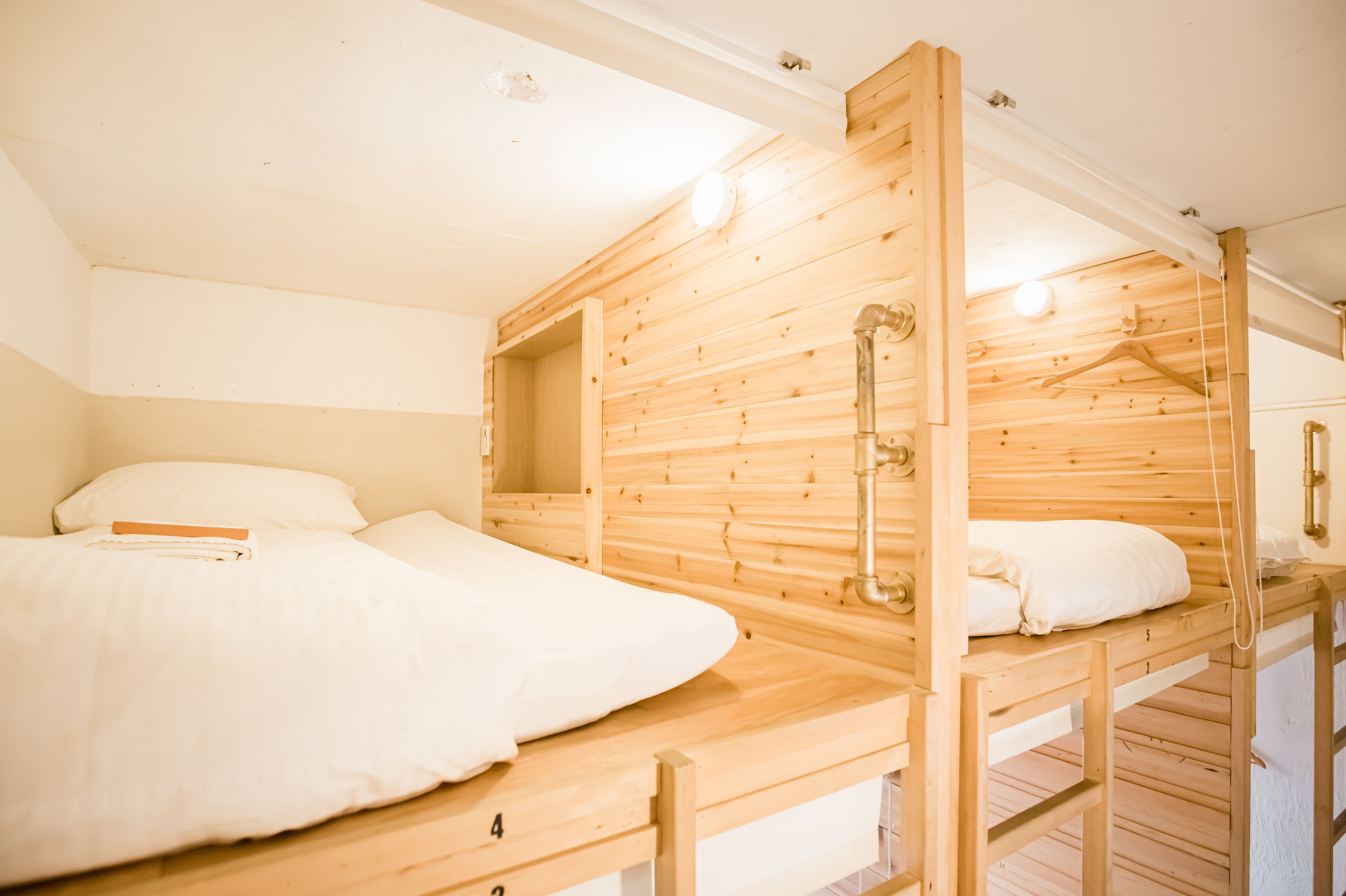 Un dormitorio con literas de madera, ropa de cama blanca y una lámpara colgante.