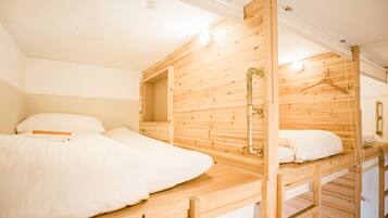 Un dormitorio con literas de madera, ropa de cama blanca y una lámpara colgante.